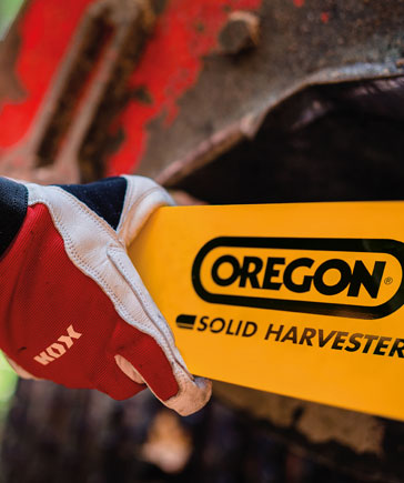 Hand met rode KOX-werkhandschoenen houdt een gele oogstzaagblad vast met OREGON-logo en opschrift Solid Harvester.